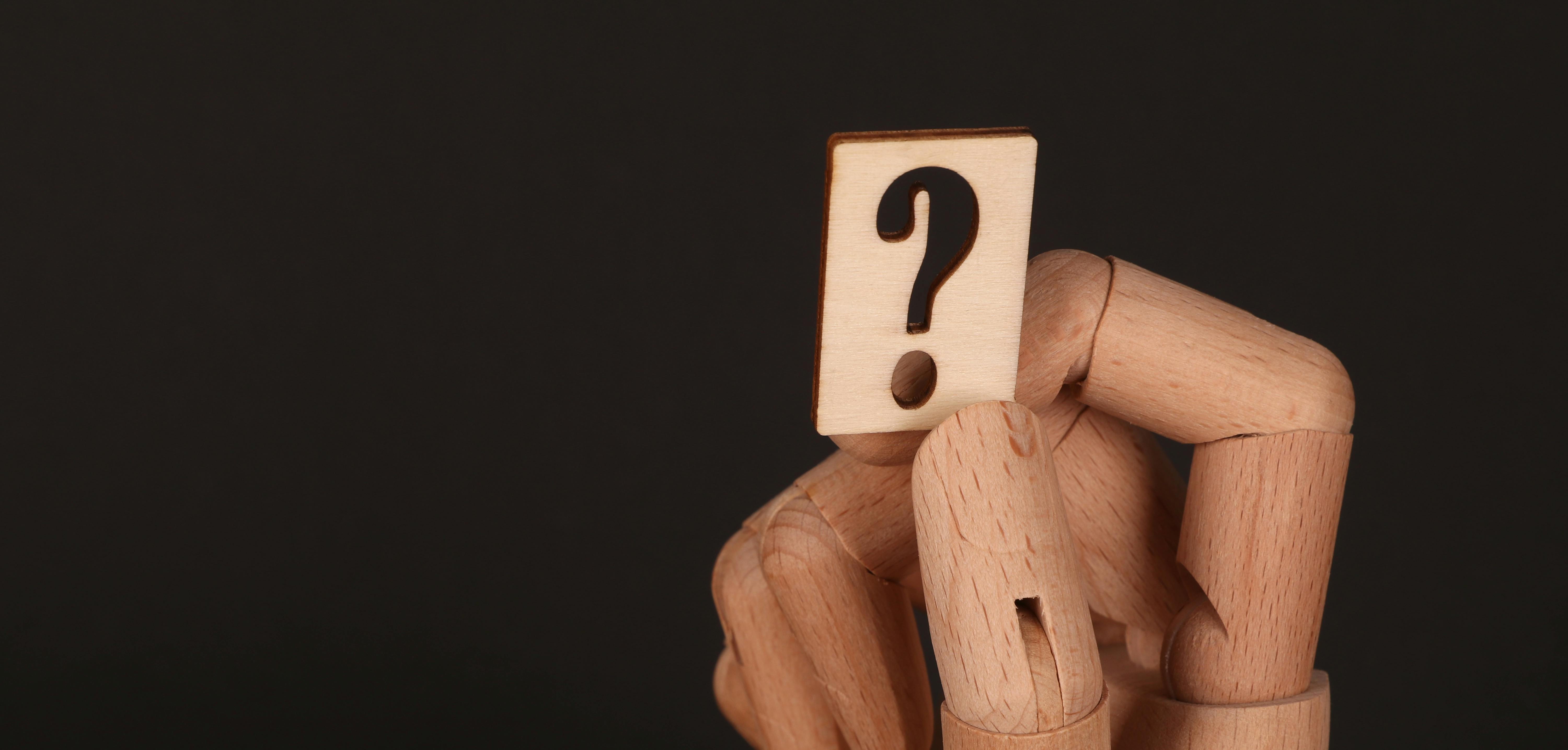 Wooden hand with a token question mark on it.